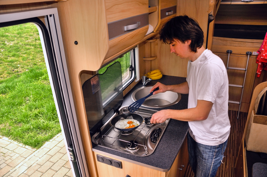 Caravan kitchen with two-burner gas cooktop in use